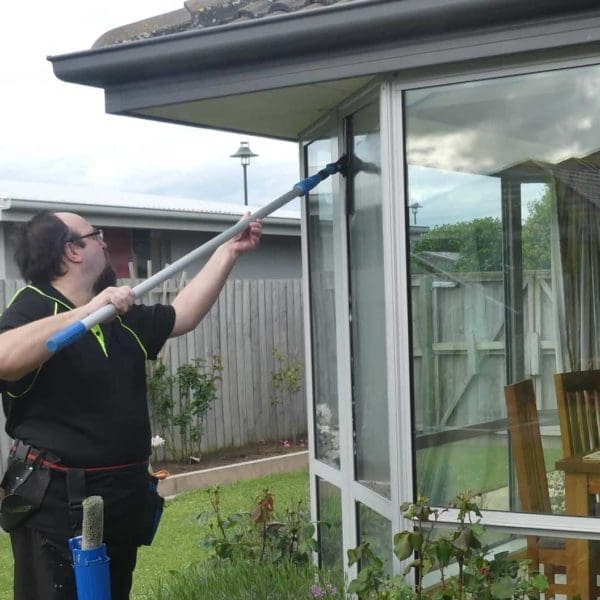 Professional cleaner using high-quality equipment to clean residential windows in Christchurc